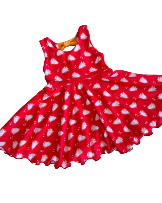 A red sleeveless dress with a white arrowhead pattern, laid flat on white floor