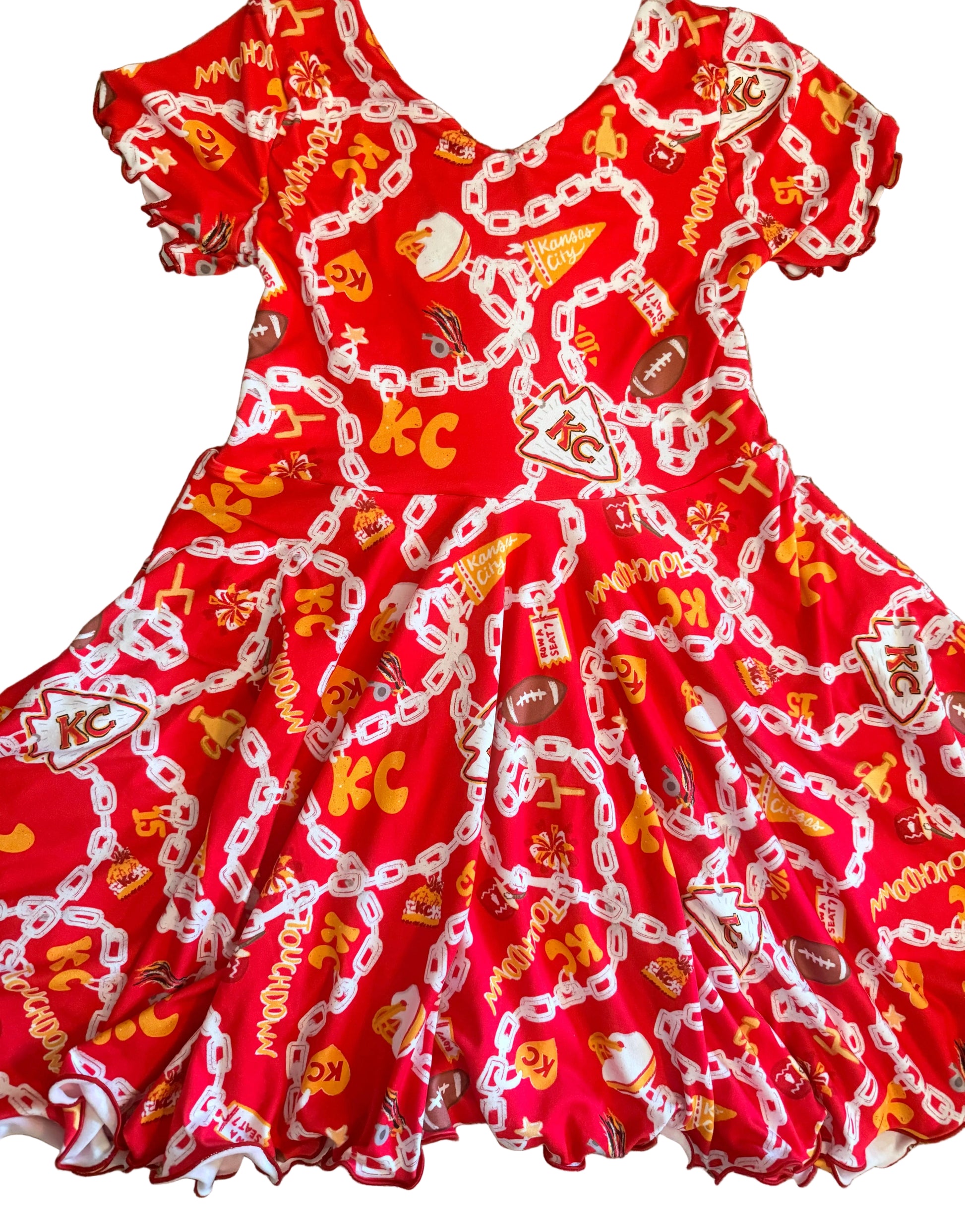 A red ruffled dress  laid flat on white floor featuring a white chain pattern with football and KC graphics