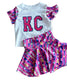 Children's outfit with 'KC' shirt and pink shorts on a textured surface