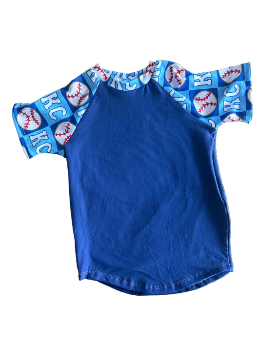 Blue fabric with baseball-themed trim on a stone surface