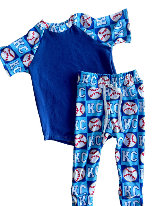 Blue children's outfit with 'KC' and baseball pattern on a textured surface