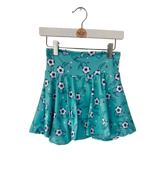 Teal skirt with kc soccer pattern hanging on a brick wall