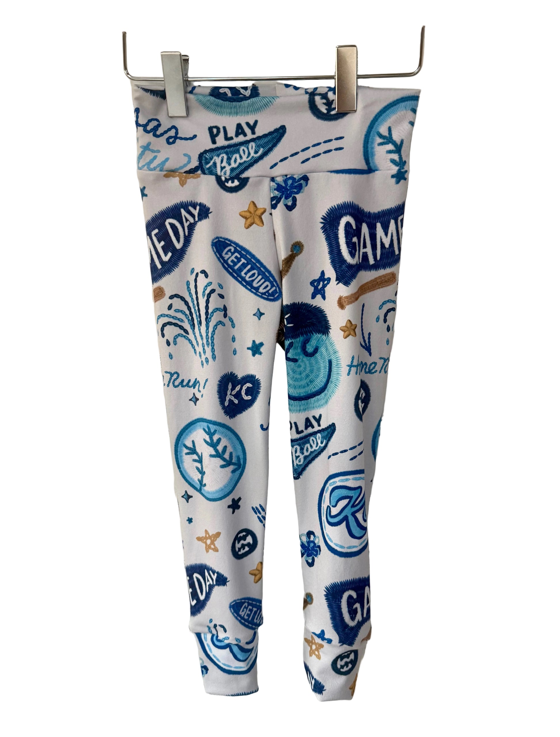 Leggings with blue kc baseball graphics on a white brick wall background