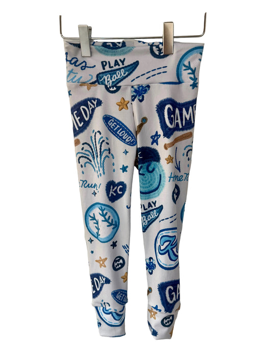 Leggings with blue kc baseball graphics on a white brick wall background
