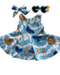 Children's blue dress with sports-themed print on a wooden surface, accompanied by a headband and sunglasses.